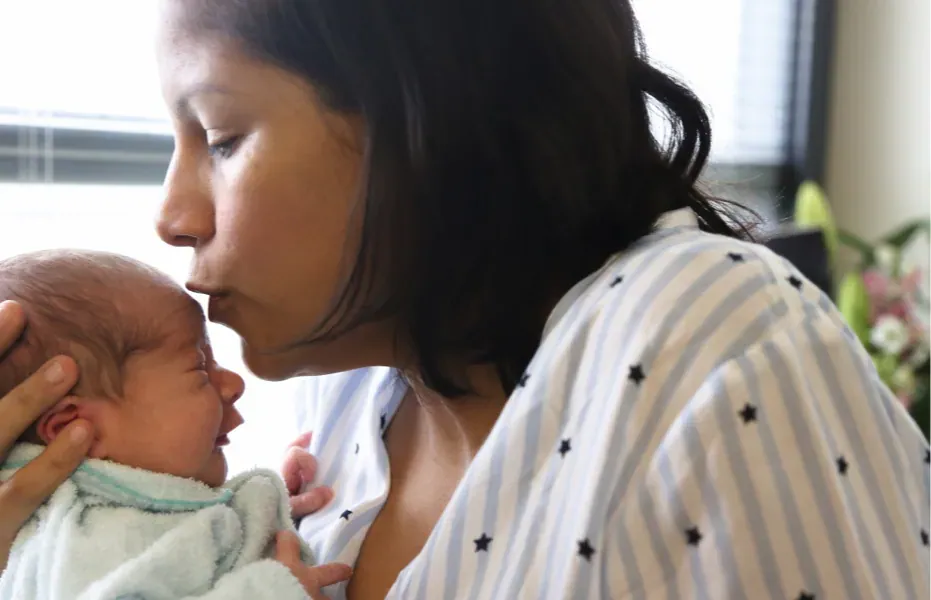 Mother kissing newborn baby on the forehead