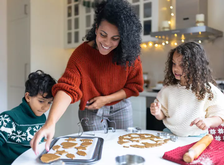 A mother baking holiday cookies with her young son and daughter at the kitchen table