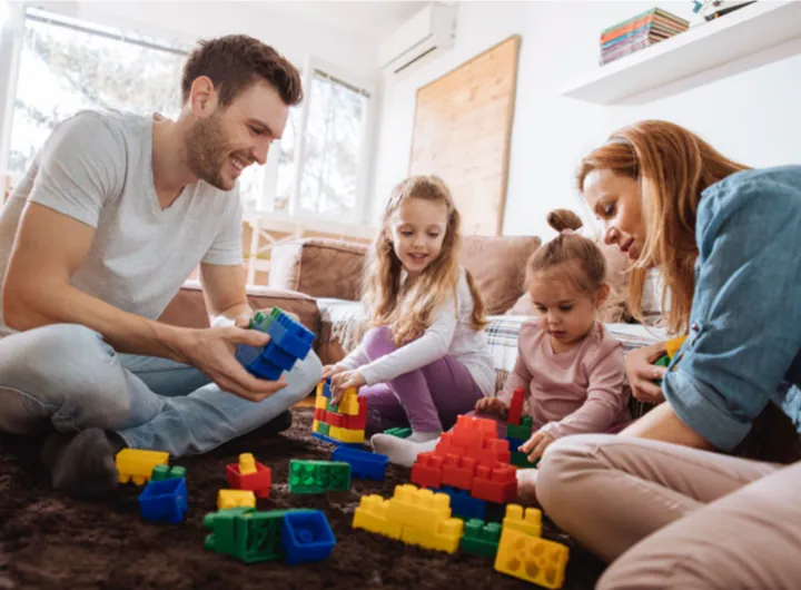 A family of four working together to plant greenery in their backyard garden on a sunny day