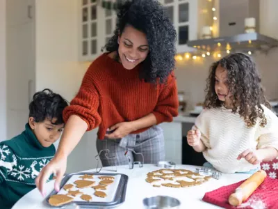 A mother baking holiday cookies with her young son and daughter at the kitchen table