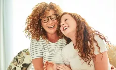 img-mother-and-daughter-on-cauch-laughing-1200x630px.webp