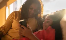 Mother and daughter using mobile phone at home