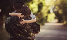 boy hugging dad in army uniform