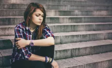 unhappy teenage girl sitting on concrete steps