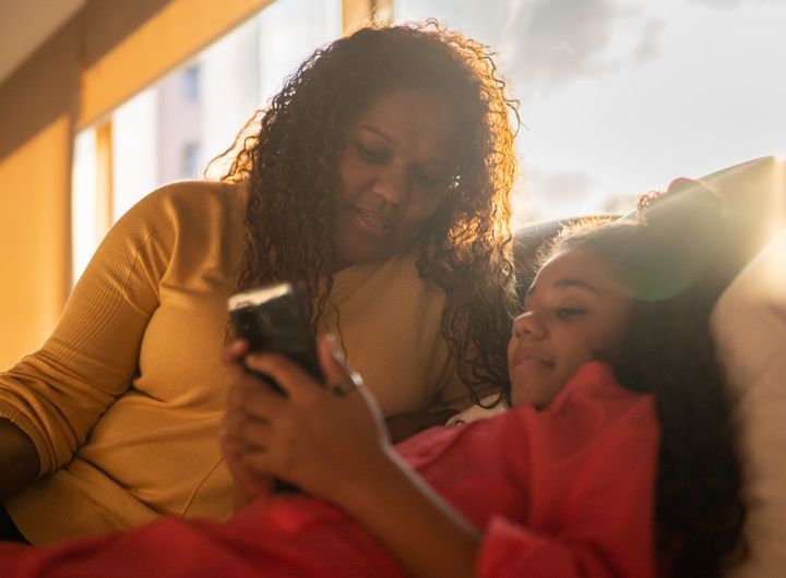 Mother and daughter using mobile phone at home